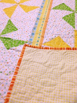 Pinwheel baby quilt with free motion quilting on flannel backing.